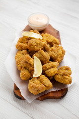 Homemade tasty japanese fried chicken Karaage on a rustic wooden board over white wooden background, side view.