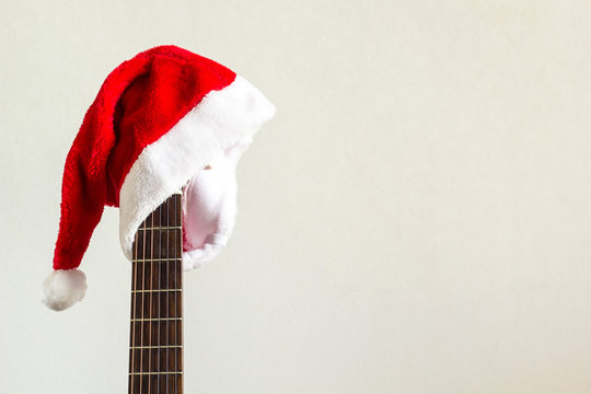 Acoustic Guitar With Red Santa Hat. Christmas Song Music Concept On White Background