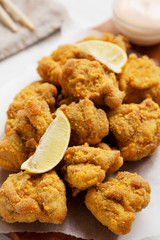 Homemade traditional japanese fried chicken Karaage on a rustic wooden board over white wooden background, low angle view. Close-up.