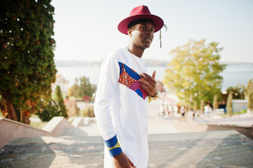 Stylish trendy afro france man in red hat and white outfit posed at autumn day. Black african model...