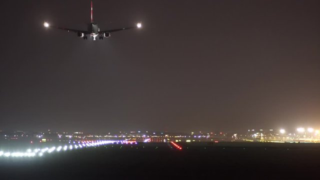 The plane lands at the airport at night.