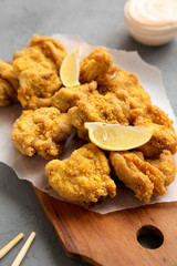 Homemade traditional japanese fried chicken Karaage on a rustic wooden board over gray surface, low angle view. Close-up.