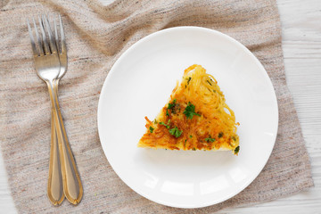 Homemade spaghetti omelette on a white plate on a white wooden background, overhead view. Flat lay, top view, from above.