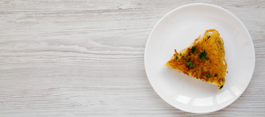 Homemade spaghetti omelette on a white plate on a white wooden surface, top view. Flat lay, overhead, from above. Space for text.