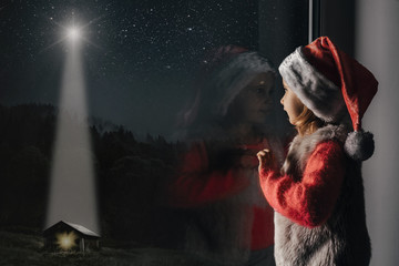 child looks out the window on christmas of Jesus Christ.