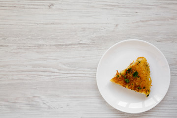 Homemade spaghetti omelette on a white plate on a white wooden background, top view. Flat lay, overhead, from above. Copy space.