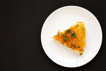 Homemade spaghetti omelette on a white plate over black background, top view. Flat lay, overhead, from above. Copy space.