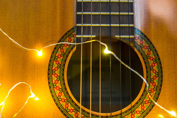 Obraz premium acoustic guitar wrapped in a luminous garland. Christmas gift
