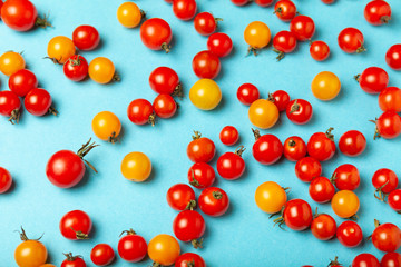 Red and yellow cherry tomatoes on blue background. Fresh bright organic vegetables.