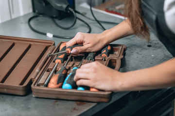 female hands and brown case with screwdrivers in the garage