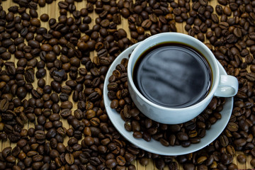 a cup of coffee with cookies, coffee grains scattered on a table near a cup with a coffee