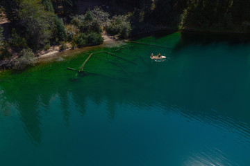 Boat on beautiful blue mountain lake, aerial view, tranquil landscape. Kolsay, Kazakstan