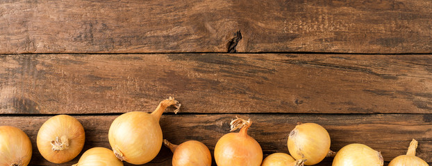 Onions on rustic wooden background with copyspace. Top view. Banner