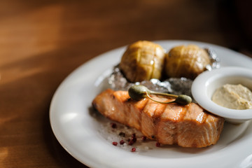 grilled salmon steak and baked potatoes with sauce