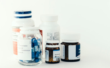 Medicine bottles with pills or capsules on white background with copy space. Drug prescription for treatment medication closeup top view.
