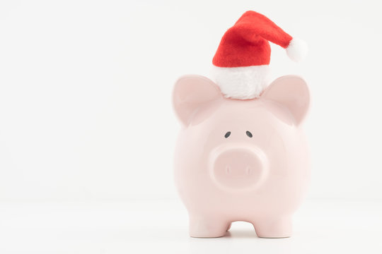 Concept image for savings planning featuring a pink piggy bank wearing a red Santa hat. 