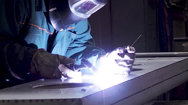 Static shot of worker welding stainless steel part, using TIG, MIG, welder, close up. The welder uses a mask to protect your eyes. Scene B.