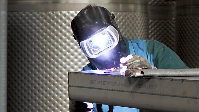 Static hot of worker welding stainless steel part, using TIG, MIG, welder, close up. The welder uses a mask to protect your eyes. Scene D.