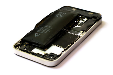 Swollen lithium ion polymer battery inside a mobile phone on white background isolated