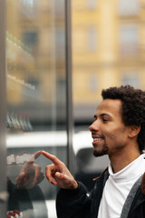 African man buys drink or sweets at vending machine outside.