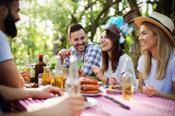 Group of happy friends eating and toasting at garden barbecue