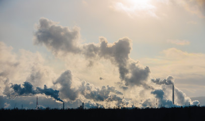 Fototapeta na wymiar Factory chimneys pollute the atmosphere with dense smoke.
