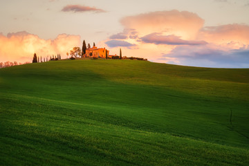 Amazing spring landscape with green rolling hills and farm houses in the heart of Tuscany in golden hour before sunset
