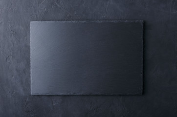 Top view of slate table mat on the black surface.Empty space for design