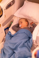 1-year-old baby girl peacefully sleeping on the plane in business class comfort