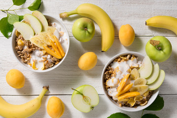 Plates with granola and fruits on a white wooden background. Healthy breakfast cereal