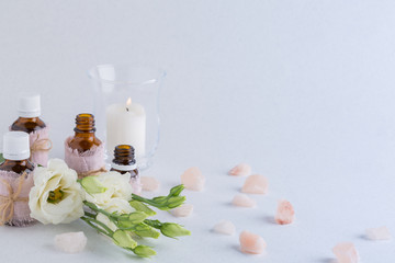 Spa composition with oils, sea salt, candles and a branch of white eustoma on a white background