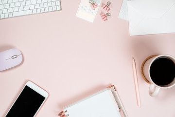 Flat lay office table desk. Minimal women office desktop with keyboard, laptop mouse, phone, pen, coffee mug and notebook on pink background. Top view, space for text.