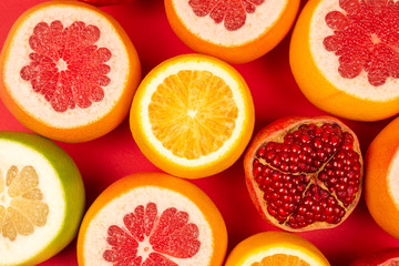 Grapefruit, orange, pomegranate, citrus sweetie on red background. - obrazy, fototapety, plakaty
