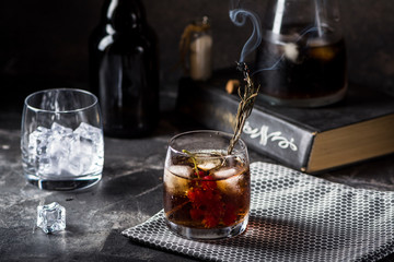 Cuba Libre or long island iced tea cocktail with strong drinks, cola, lime and ice in glass, cold longdrink or lemonade. Cocktail with fire. Cocktail with smoke.