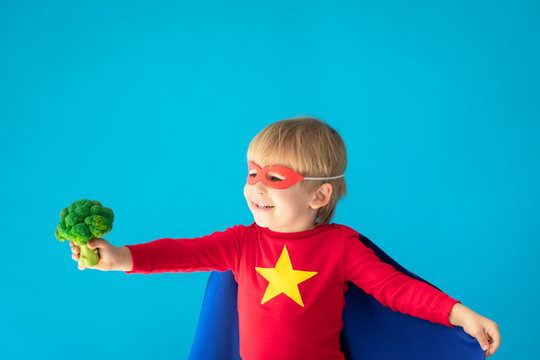 Superhero child holding broccoli