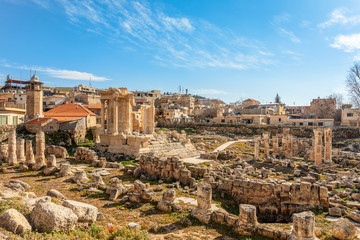 Fototapeta na wymiar The ruins and only fragment of Venus temple left with modern houses and blue sky in the background, Beqaa Valley, Baalbeck, Lebanon