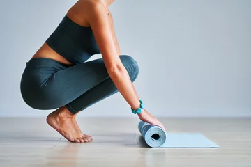Fototapete Yogaschule Junge Frau, die zu Hause Yogamatte rollt