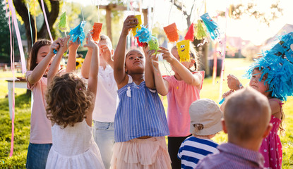 Small children standing outdoors in garden in summer, playing.