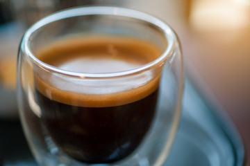 Hot espresso coffee in a clear glass, in retro coffee shop.