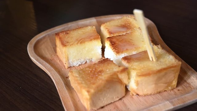 4K Hand of asian woman picking buster and sugar toast on the wood plate. Food background concept.