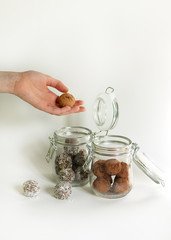 Obraz na płótnie Canvas Energy balls in a glass jar on a white background. Girl puts candies in glass jars for storage. Two different types of snacks