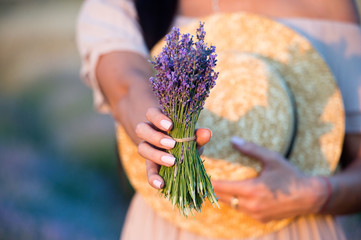 Straw hat and a bunch of lavender in the hands of women.