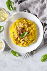 Traditional Italian risotto with mushrooms, saffron and parmesan cheese on white wooden background. Top view with copy space.