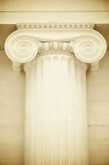 Detail close-up of the capital of a Greek Revival Ionic column in white marble featuring classical...