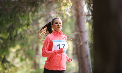 Front view of young woman running a race competition in nature.