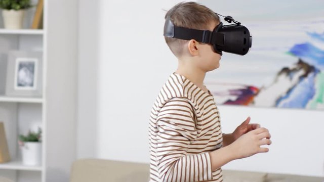 Caucasian boy with virtual reality glasses having fun while his grandfather sitting with newspaper and grandmother using tablet while sitting on sofa