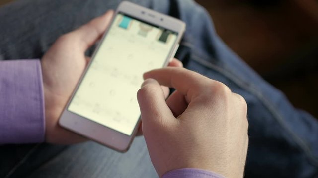 A man looks at the goods in the online clothing store. People using Smartphone, online shopping. The screen is blurred. Close-up. 4K UHD.