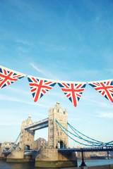 Classic blue sky view of Tower Bridge with vintage Union jack pennant bunting in London, UK