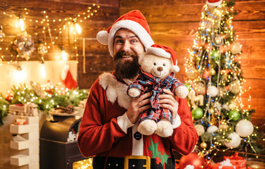 Crazy, funny Hipster Santa. Santa man posing with teddy on vintage wooden background.