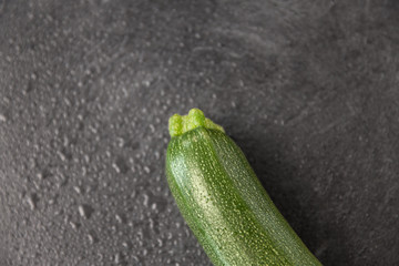 vegetable, food and culinary concept - close up of zucchini on slate stone background